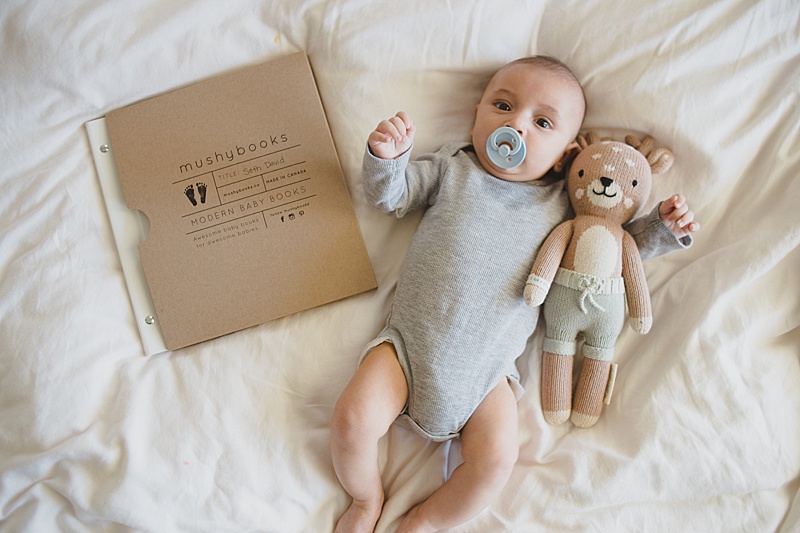 baby with baby book on a bed