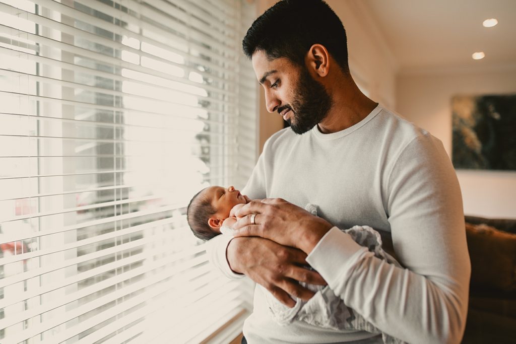 New dad holding his brand new baby son. Grab this checklist to help you prepare for your newborn baby!