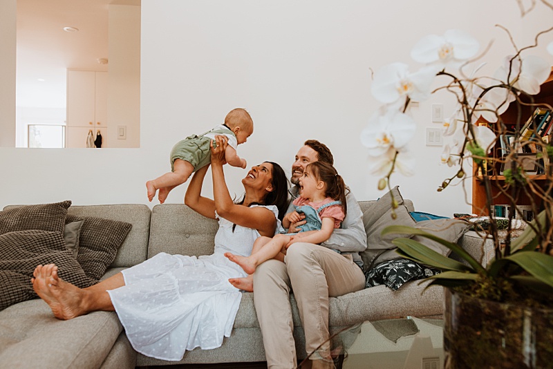 Family snuggled up on their couch. Find the perfect outfit for date night or a family session with the best North Vancouver shopping locations.