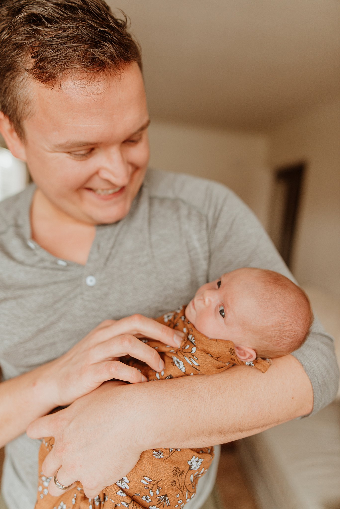 A happy father smiles while tickling his newborn baby in his arms after finding a vancouver diaper service