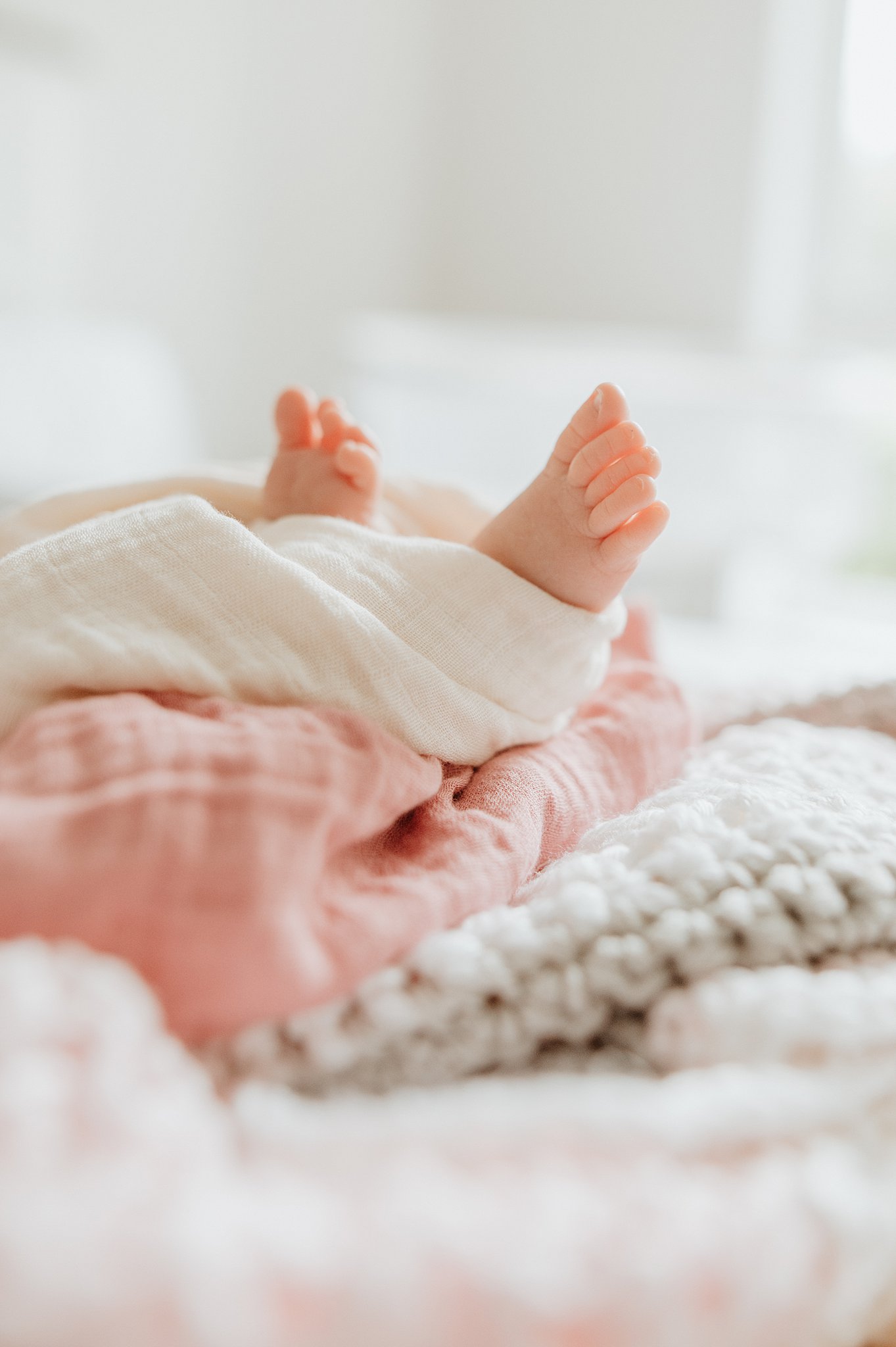 Details of a newborn baby's feet sticking out of a blanket