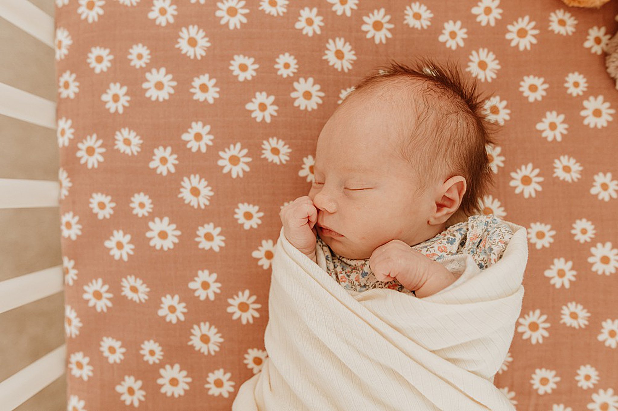 A newborn baby sleeps on a daisy crib mattress