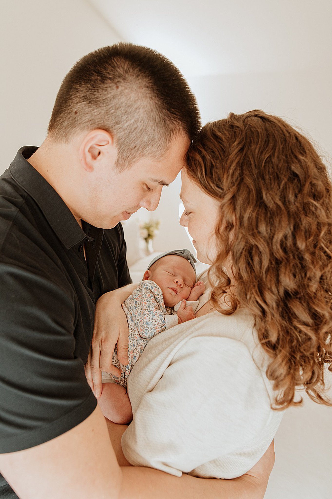 Happy new parents cradle their sleeping newborn baby while touching foreheads after meeting nannies on call vancouver