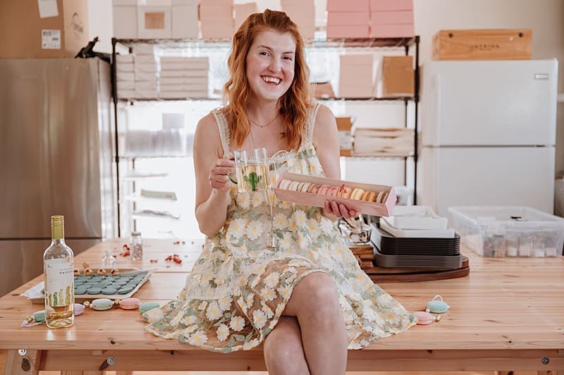 Lifestyle portrait of Kizzy holding a box of macarons in her kitchen during her brand photography session