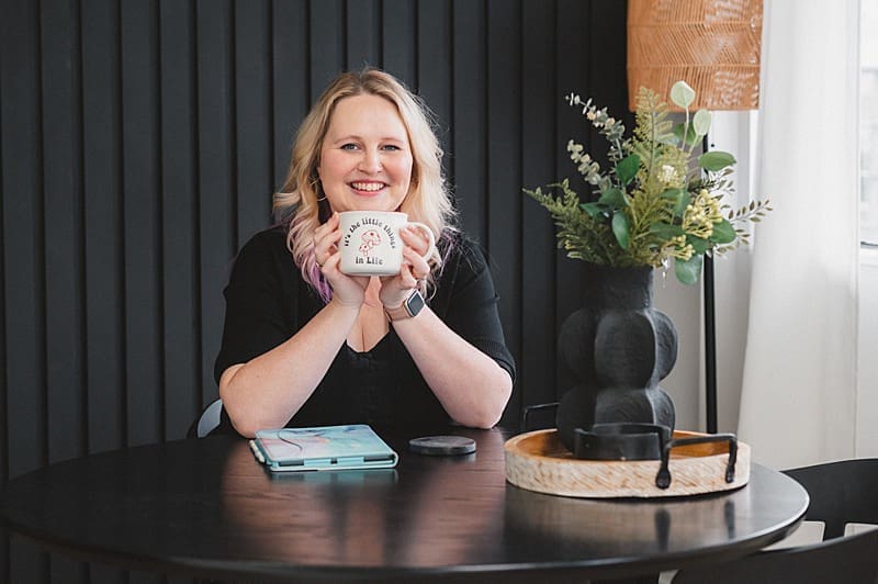 Digital marketer smiling with coffee in workspace during brand photo session

