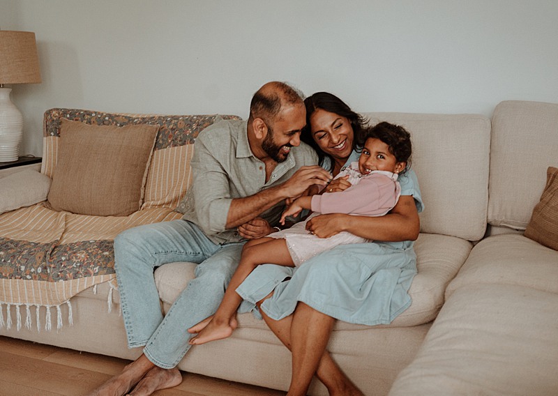 family of three snuggling on the couch in the living room during their in home family photography session in Vancouver