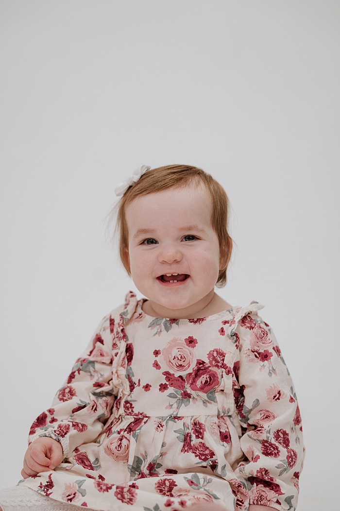 Toddler girl grins widely full of personality during portrait session.