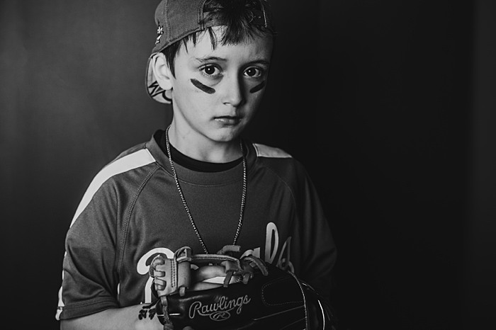 Young boy in baseball gear during children's portrait session. School age is one of the best ages for portrait sessions to capture passion and personality.
